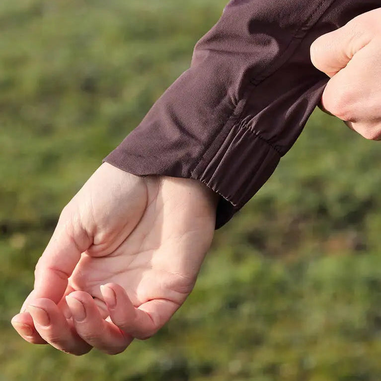 Close-up of a person's hand wearing a brown sleeve against a blurred green background