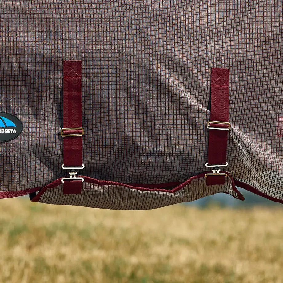 Close-up of a horse blanket with straps on a grassy background