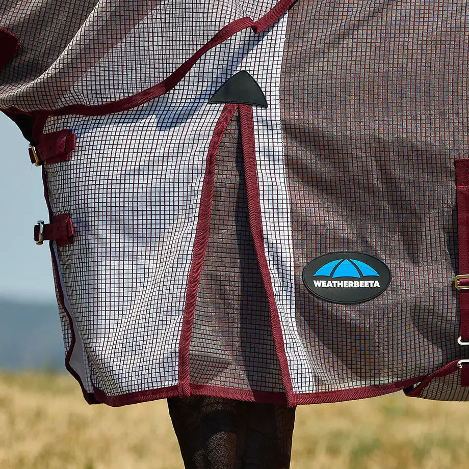 Horse wearing a mesh fly sheet with Weatherbeeta logo in an outdoor setting