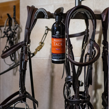 Bottle of tack conditioner on a wall with horse tack equipment.