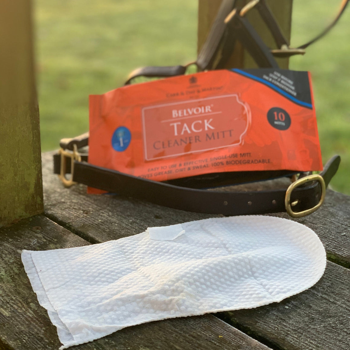 Tack cleaner mitt and packaging on a wooden surface with a grassy background