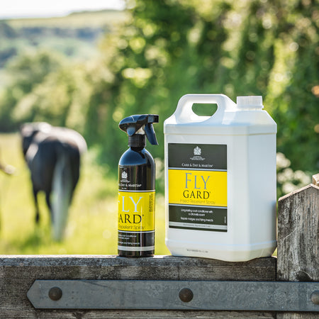 Fly Gard products on a wooden fence with a field and person in the background