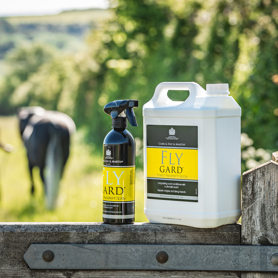 Fly Gard products on a wooden fence with a field and person in the background