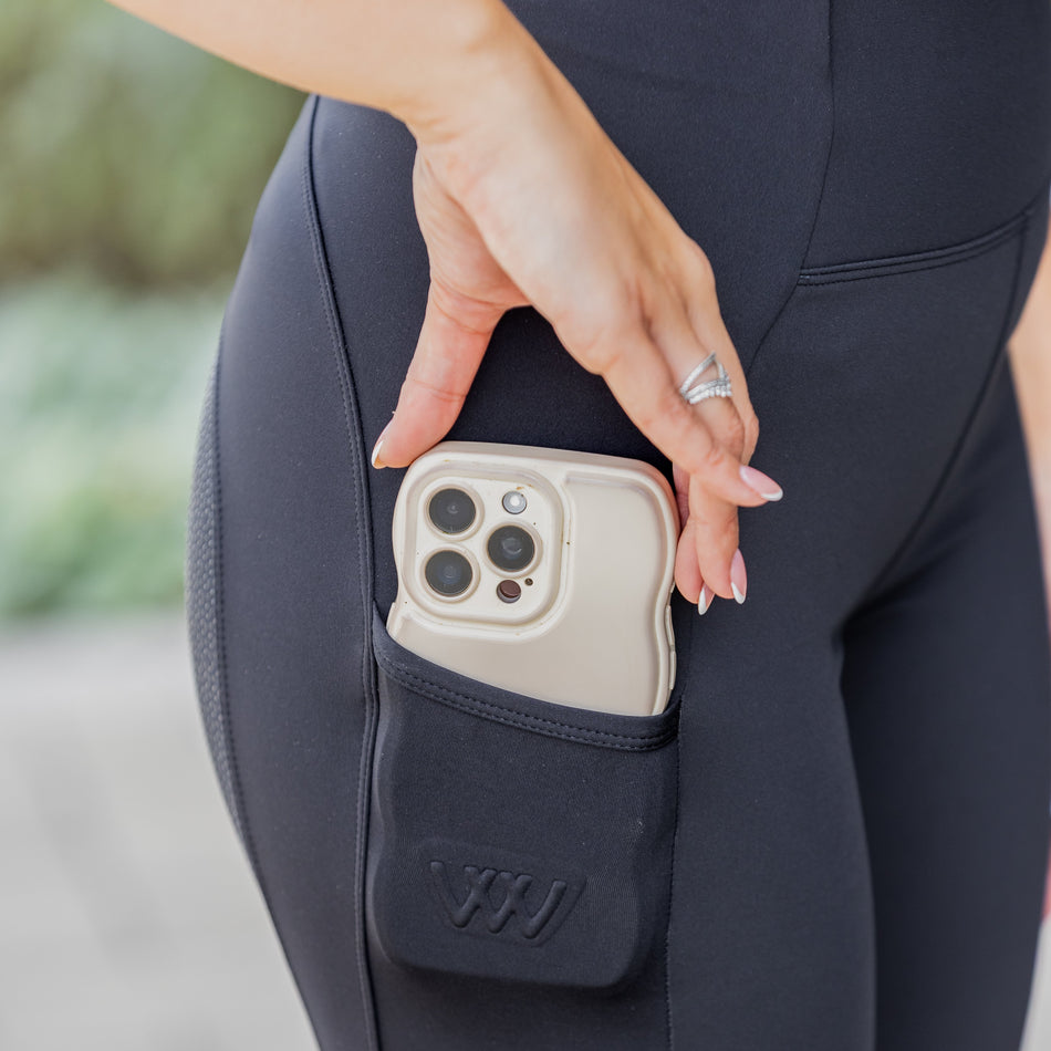 Person wearing dark leggings with a phone pocket holding a phone.