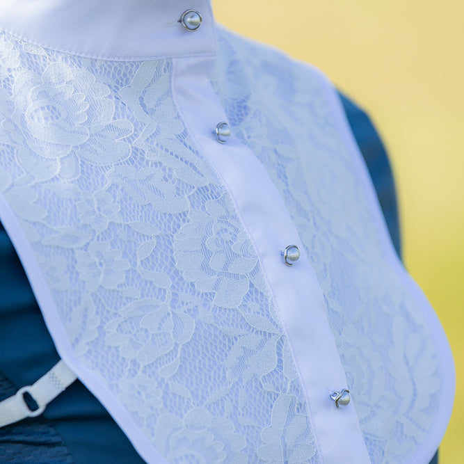 Close-up of a white lace garment with buttons on a yellow background